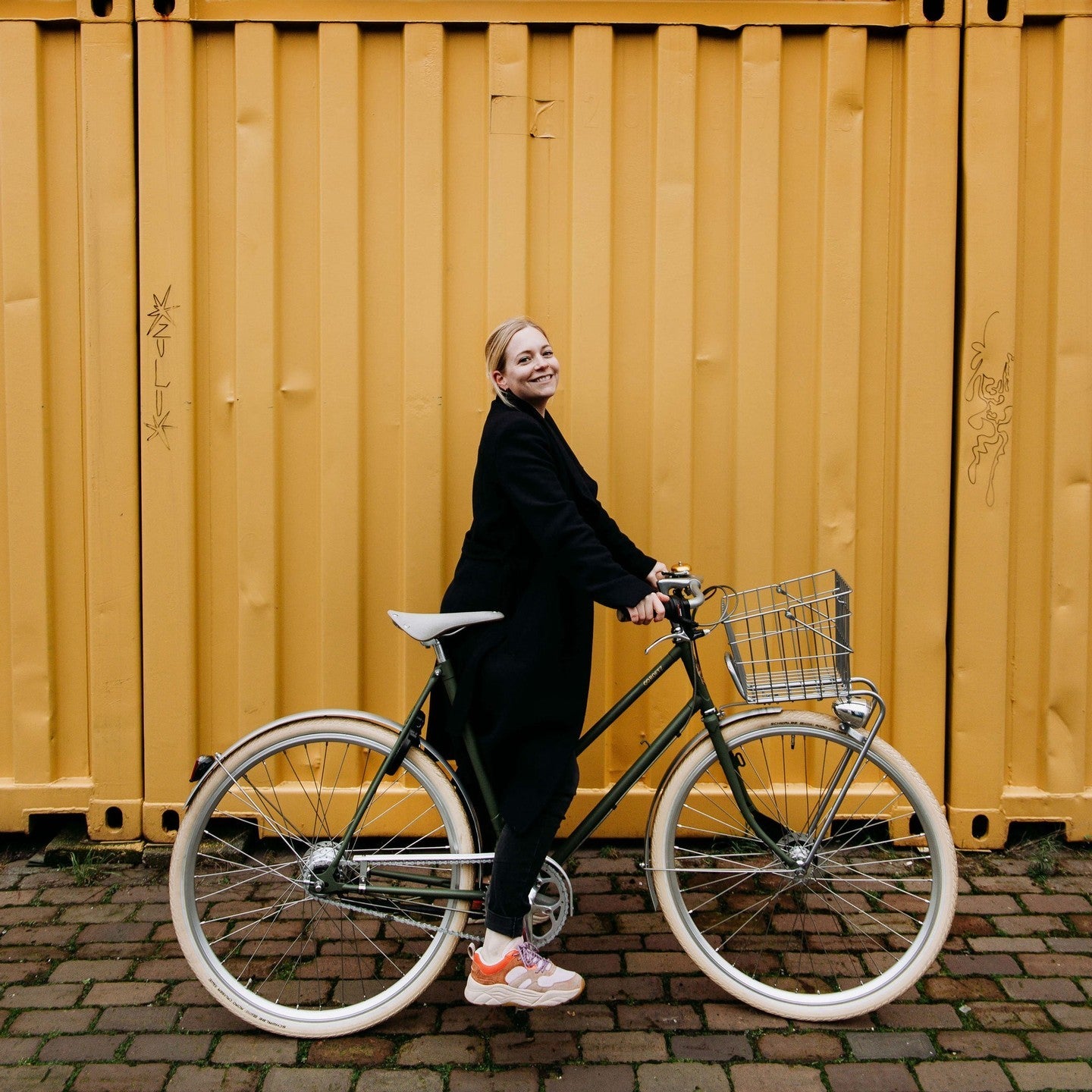 Dame met Roetz Vigour Ladies in de kleur Matt Moss green met op de achtergrond gele metalen containers