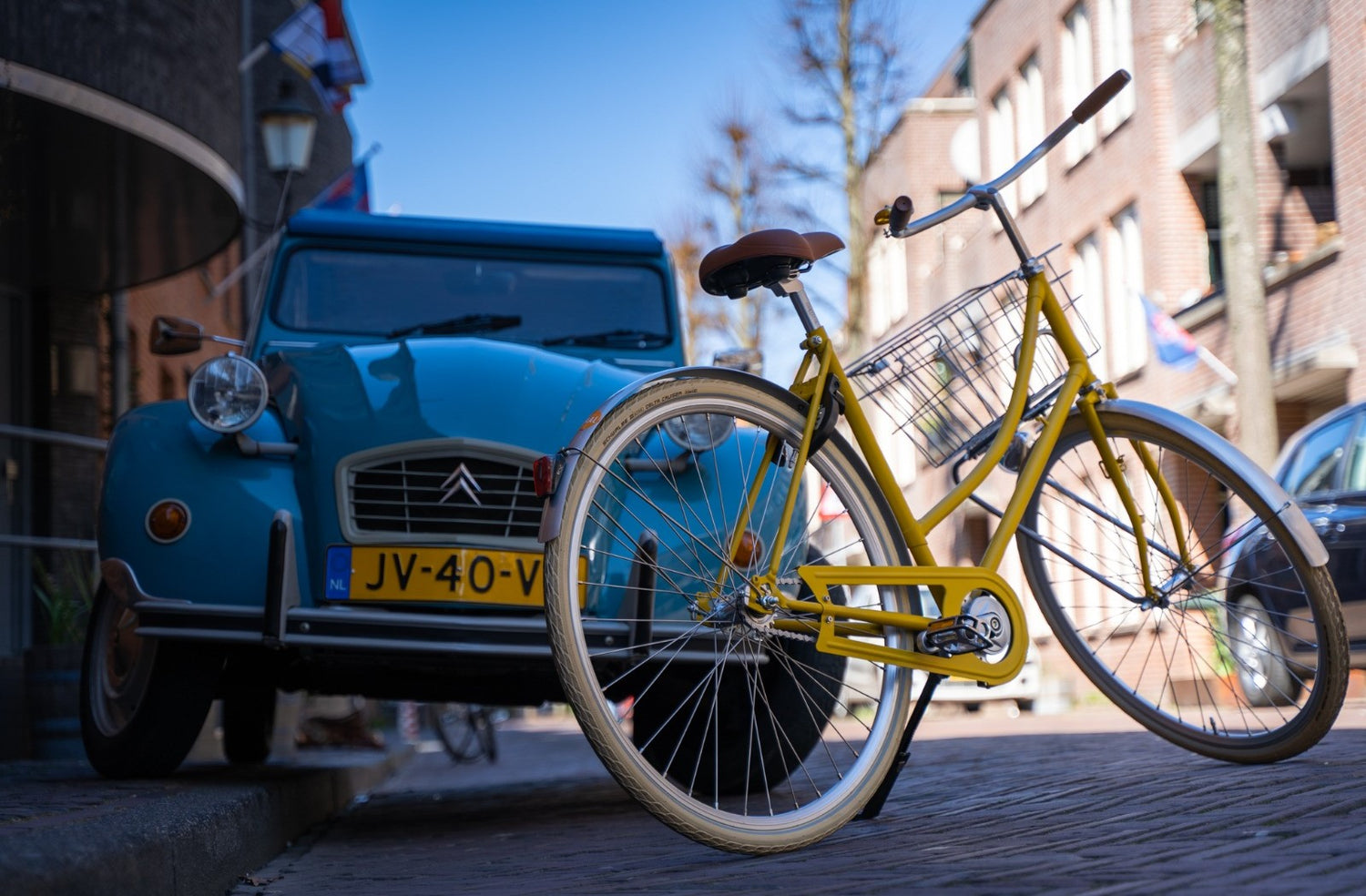 Roetz Road Ladies in mat rebel yellow met op de achtergrond blauwe Deux Chevaux. Klik voor de collectie van Roetz bikes.