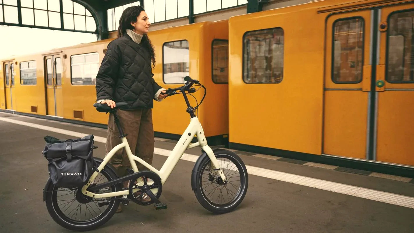 Een vrouw met een TENWAYS CGO Compact op het perron, naast een gele trein